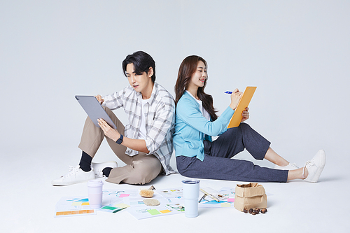 협동 비즈니스_양반다리를 하고 태블릿을 들고 이야기를 나누는 앉아있는 남자와 여자 사진 이미지