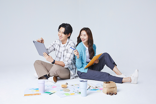 협동 비즈니스_양반다리를 하고 태블릿을 들고 이야기를 나누는 앉아있는 남자와 여자 사진 이미지