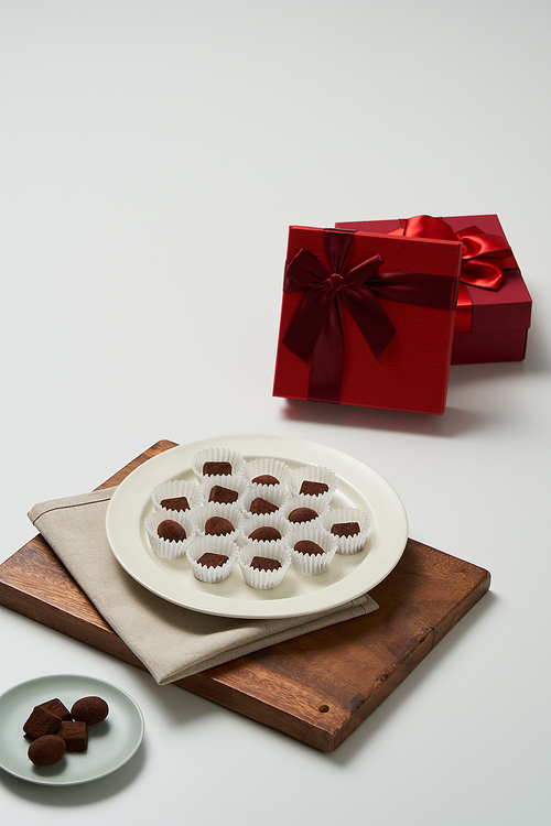 유산지컵에 수제초콜릿이 담겨있는 접시가 있고 옆에 선물상자가 놓여있다