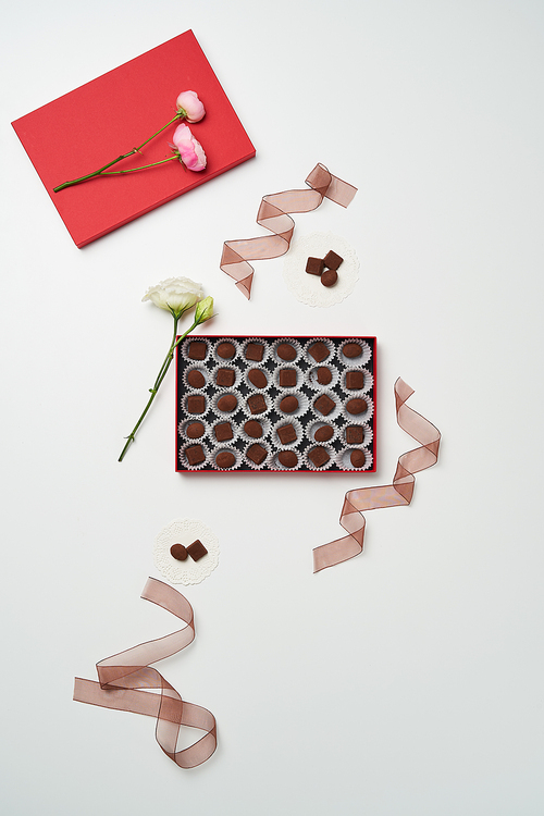 개별포장된 초콜릿이 담긴 박스가 있고 주변에 리본과 꽃이 있다