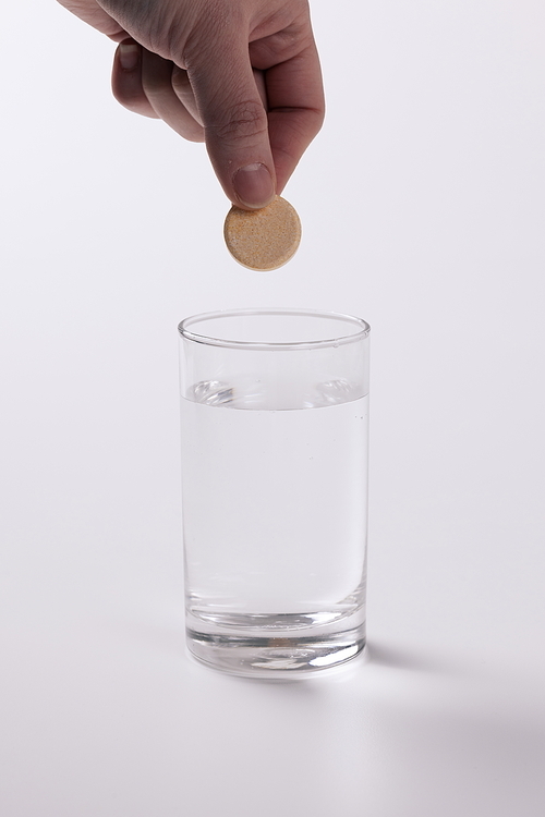 물컵에 둥근모양의 약을 넣으려는 모습