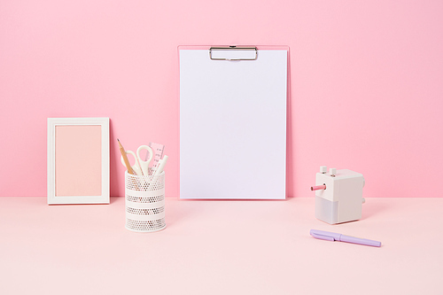 핑크색 책상위에 있는 클립보드와 사무용품들