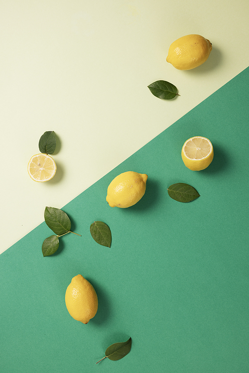 두개의 그린톤 배경에 놓인 노란색 레몬과 초록 잎사귀