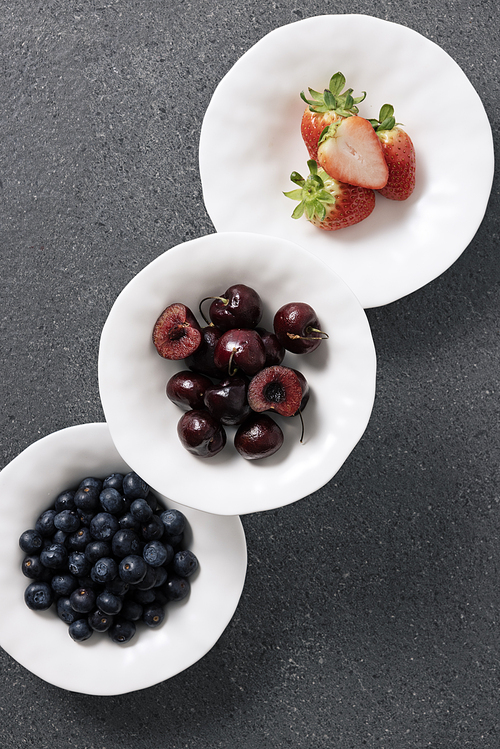 흰색접시에 각각 담긴 잘익은 베리류 과일들