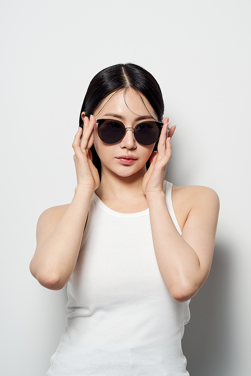 흰색배경의 양손으로 선글라스를 끼는 동양인 여성