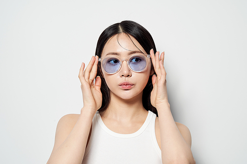 양손으로 투명한 선글라스를 끼고 한곳을 응시하는 동양인 여성