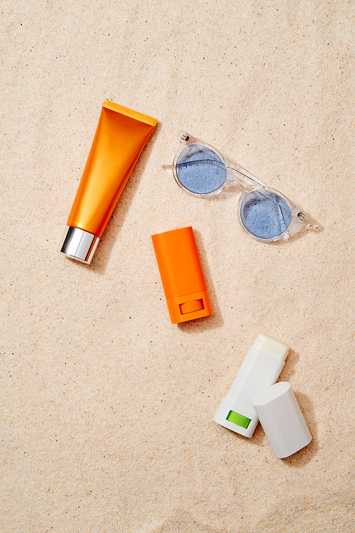 모래배경의 자외선 차단제들과 선글라스