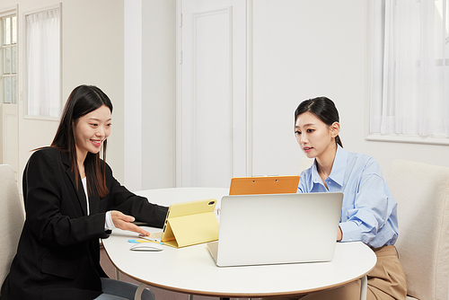 태블릿 PC와 서류를 보고 있는 2명의 동양인 여성