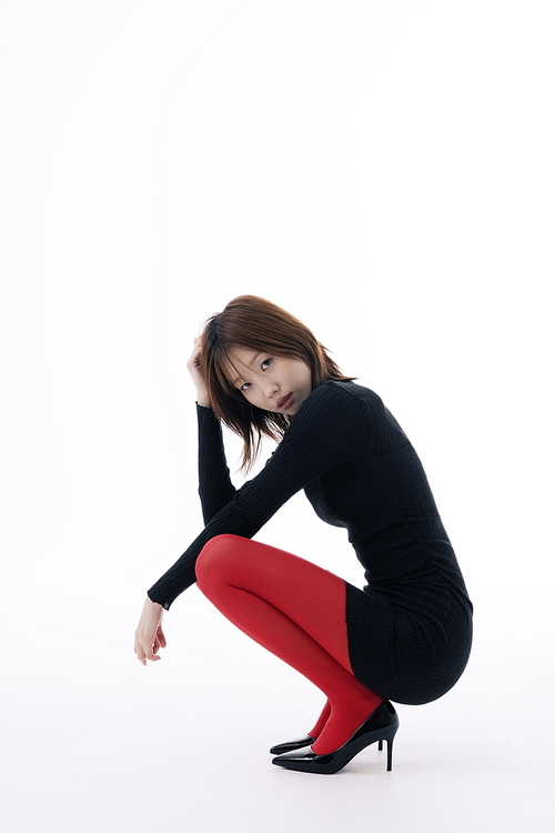 블랙 원피스와 레드레깅스를 입고 앉아있는 포즈를 취하는 한국인 여성