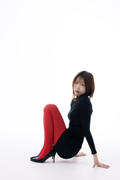 블랙 원피스와 레드레깅스를 입고 앉아있는 포즈를 취하는 한국인 여성