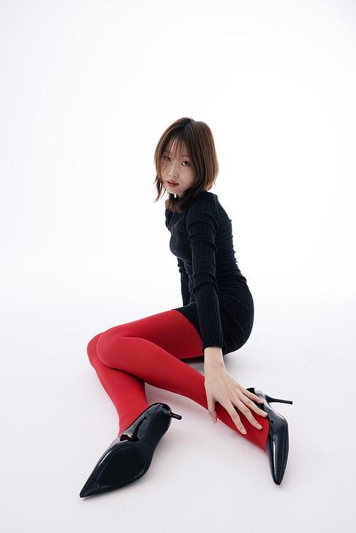 블랙 원피스와 레드레깅스를 입고 바닥에 앉아 포즈를 취하는 한국인 여성