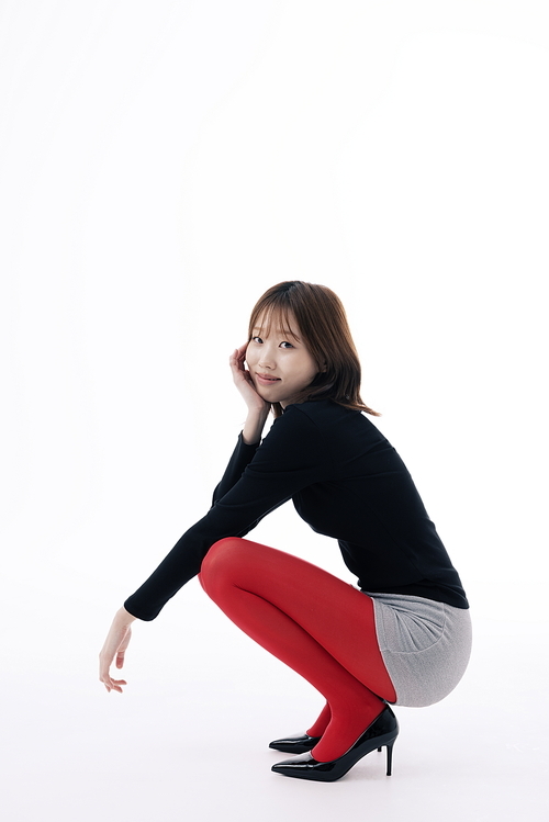 마이크로 쇼츠 의상을 입고 앉아서 포즈를 취하는 한국인 여성
