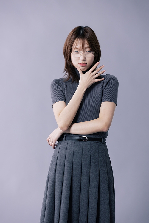 회색 의상을 입고 얼굴을 찡그리는 20대 한국인 여성