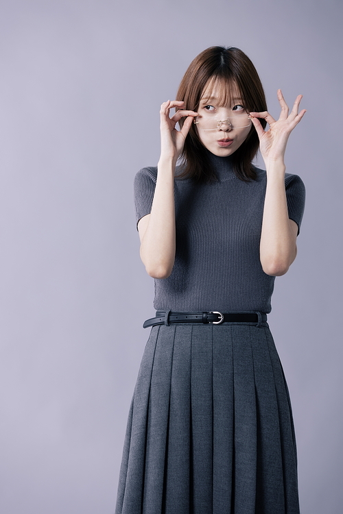 회색 의상을 입고 양손으로 안경테를 만지는20대 한국인 여성
