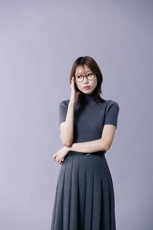 긱시크룩을 입고 한손으로 안경테를 만지는 20대 한국인 여성