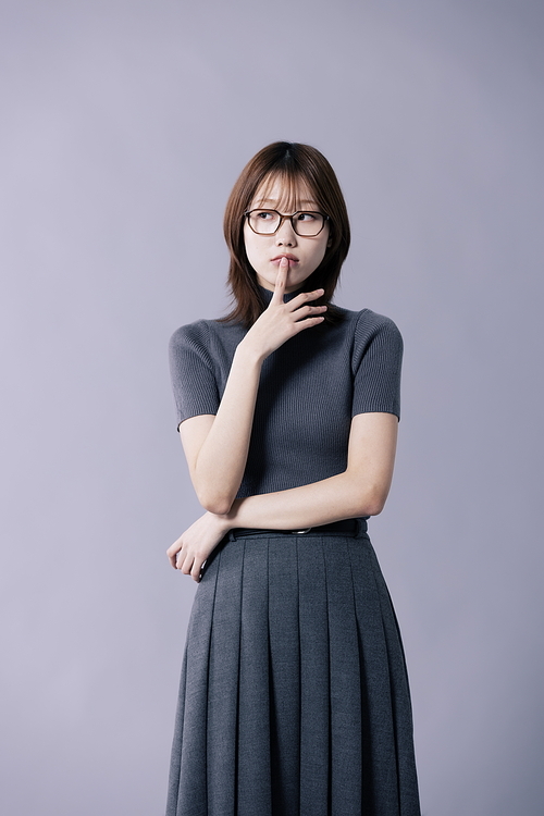 안경을 쓰고 손가락으로 입술을 만지는 20대 한국인 여성