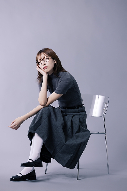 긱시크룩 스타일을 하고 의자에 걸터앉아 턱을 괴는 20대 한국인 여성