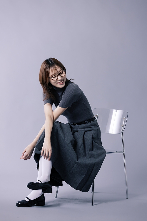 긱시크룩 스타일을 하고 의자에 걸터앉은 미소를 짓는 20대 한국인 여성