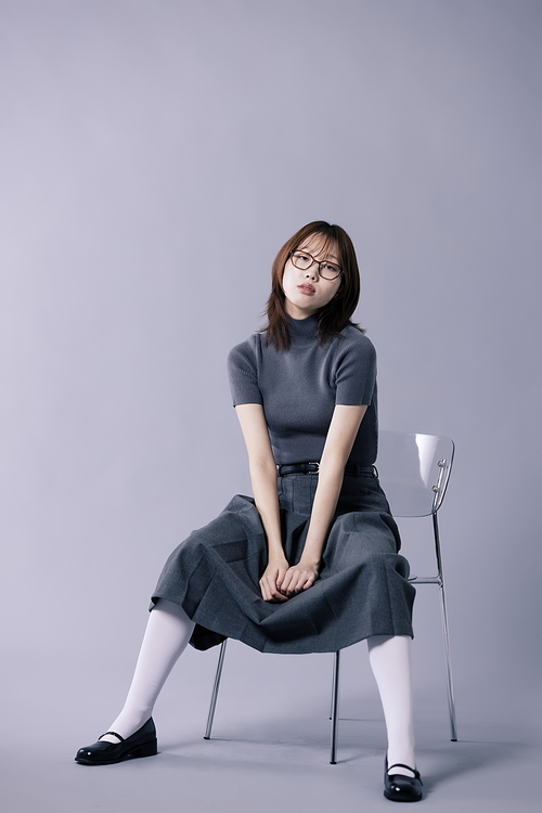 긱시크룩 스타일을 하고 다리를 꼬고 의자에 앉은 20대 한국인 여성
