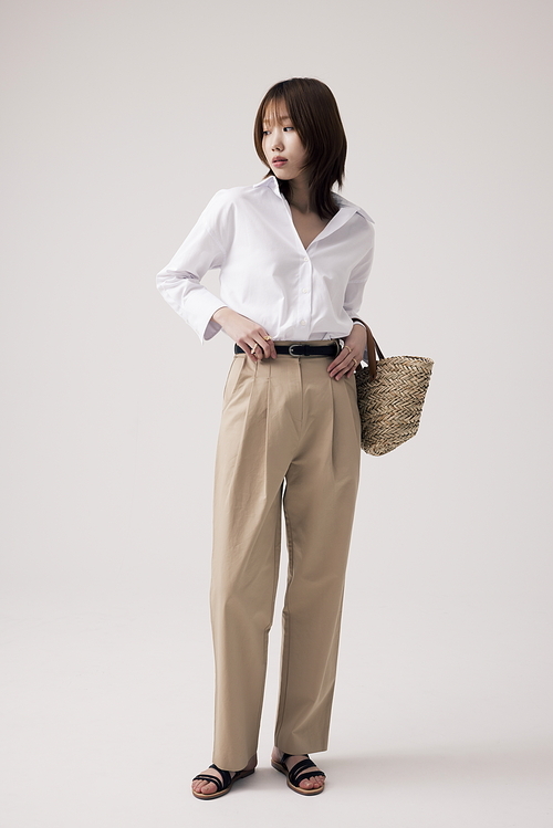 흰셔츠와 베이지 바지를 입고 가방을 든 한국인 여성