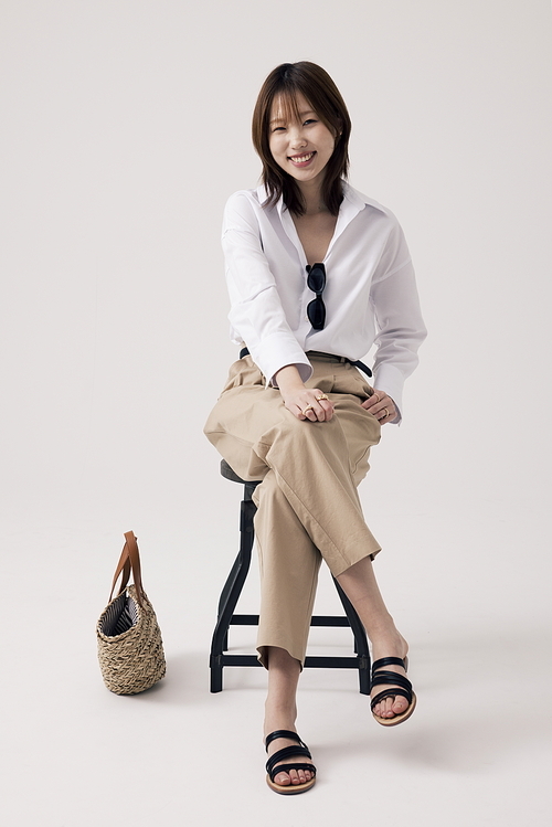 흰셔츠와 베이지 바지를 입고 의자에 앉아있는 한국인 여성