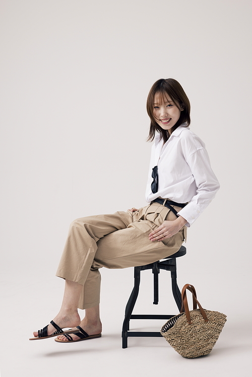 트렌디한 의상을 입고 다리를 꼬고 의자에 앉아있는 한국인 여성