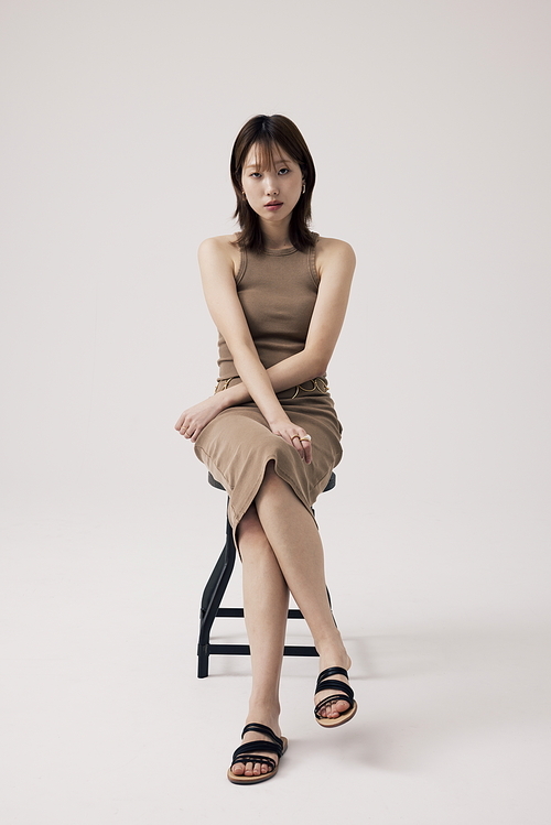 베이지 니트원피스를 입고 의자에 앉아있는 한국인 여성