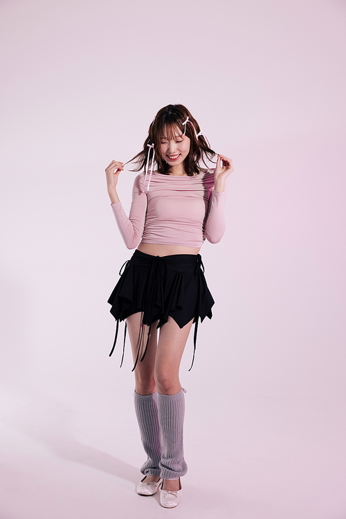 발레코어룩 스타일을 착장하고 헤어리본을 만지며 포즈를 취하는 20대 한국인 여성