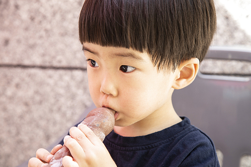 튜브에 든 아이스크림을 먹는 어린이