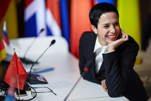Laughing woman in formalwear listening to co-worker at conference