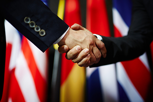 Handshake of two politicians on background of flags