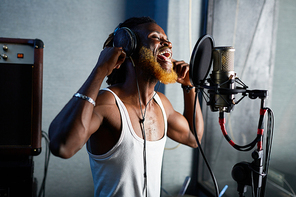 Skilled man in headphones singing his songs in microphone