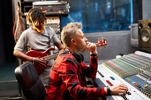 Deejay looking at screen while regulating volume on soundboard