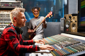 Modern sound operator sitting by stereo system and working