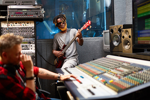 Modern performer playing guitar in recording studio