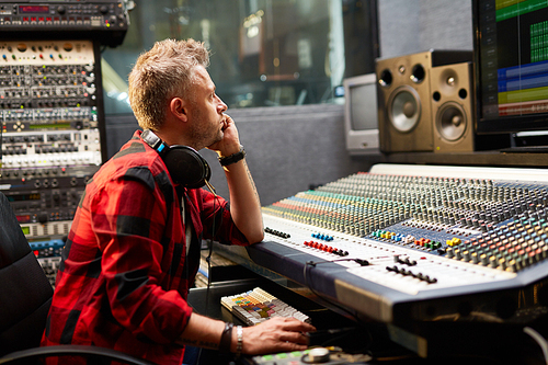 Sound-operator sitting by soundboard and looking at display