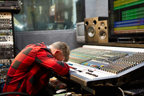 Tired deejay putting his face on soundboard in audio studio