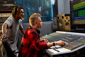 Sound-operator and his assistant looking at display with sound waves