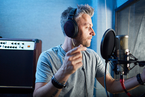 Musician in headphones recording his songs in studio