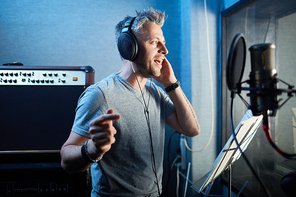 Attractive man performing his songs in studio of records