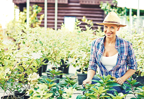 Portrait of young smiling woman sitting among plants