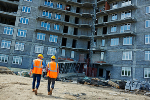 Two constructors in uniform walking down construction site