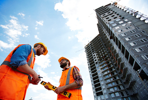 Modern inspectors talking by new building on construction site