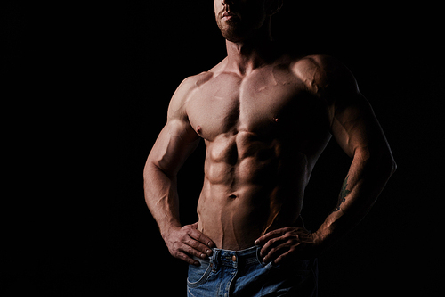 Shirtless muscular man posing over black background