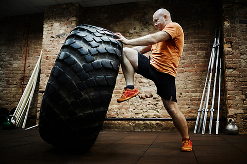 Sportsman making effort while flipping tire during workout