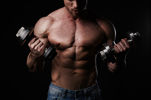 Young man lifting weights on black background