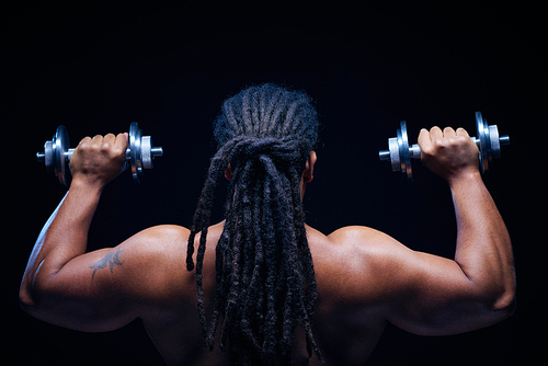 Back view of muscular African man with dreadlocks lifting barbells