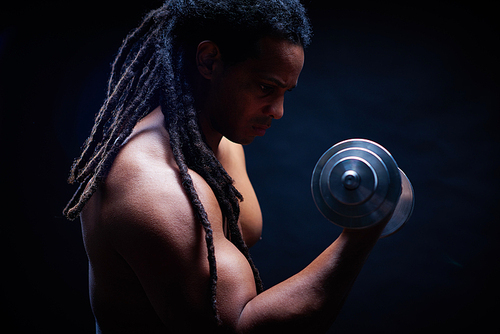 Strong bodybuilder with dreadlocks exercising in gym