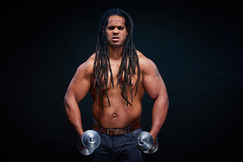 Young athlete with dreadlocks holding barbells and 