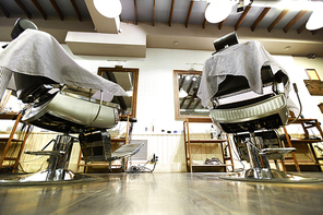 View of barbershop interior with armchairs and mirrors